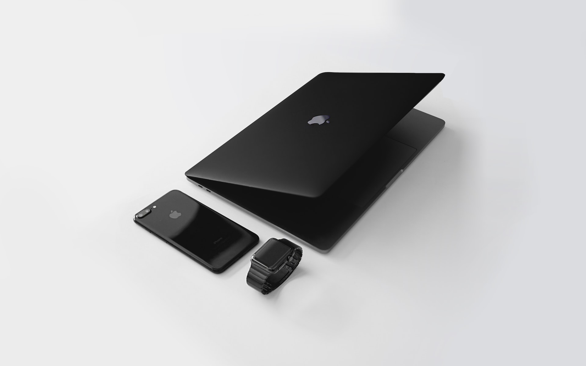 iPhone, MacBook et Apple Watch noirs maintenus ensemble